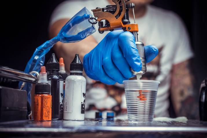 tattoo artist dipping his gun in water