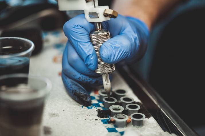 tattoo artist dipping their tattoo gun