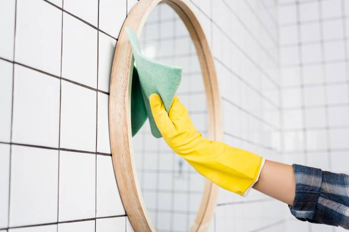 person cleaning a mirror