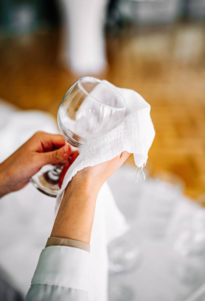 girl drying and polishing wine glass, closeup hands