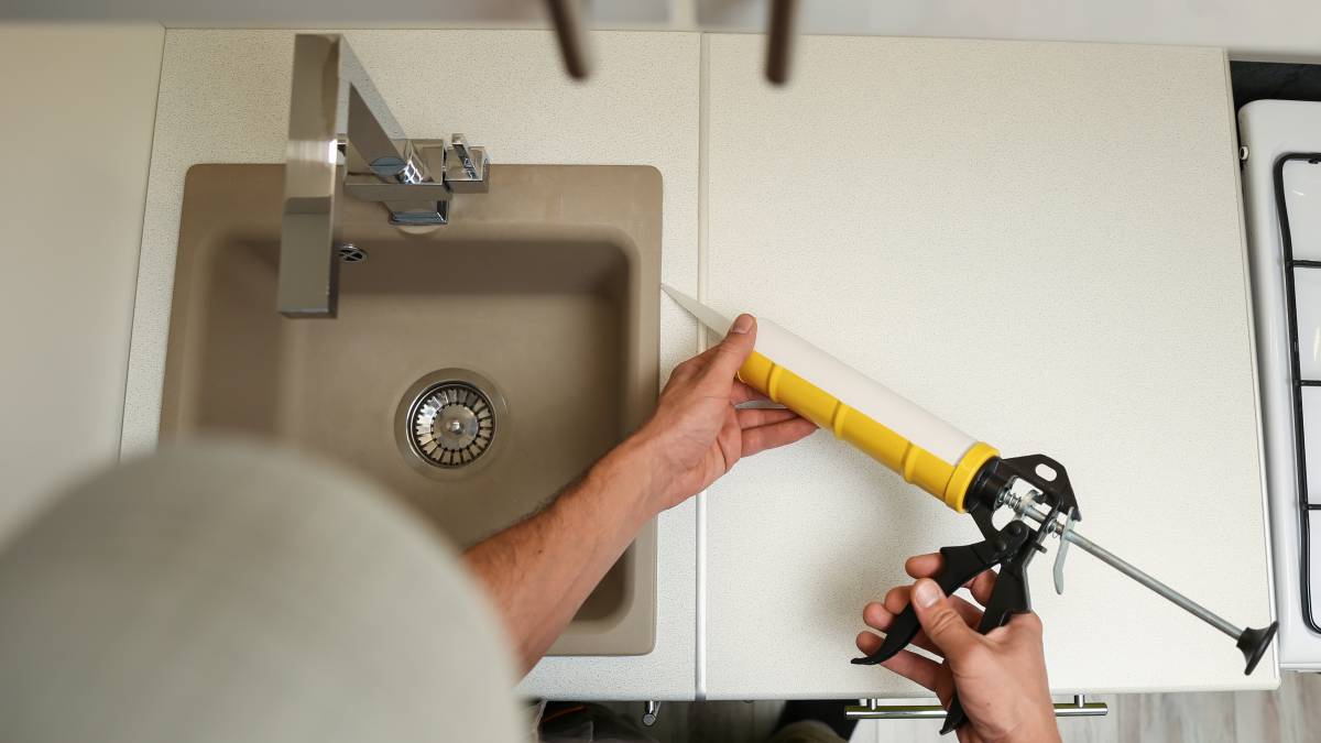 plumber putting sealant for on a newly installed kitchen sink