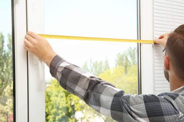 man measuring a window pane