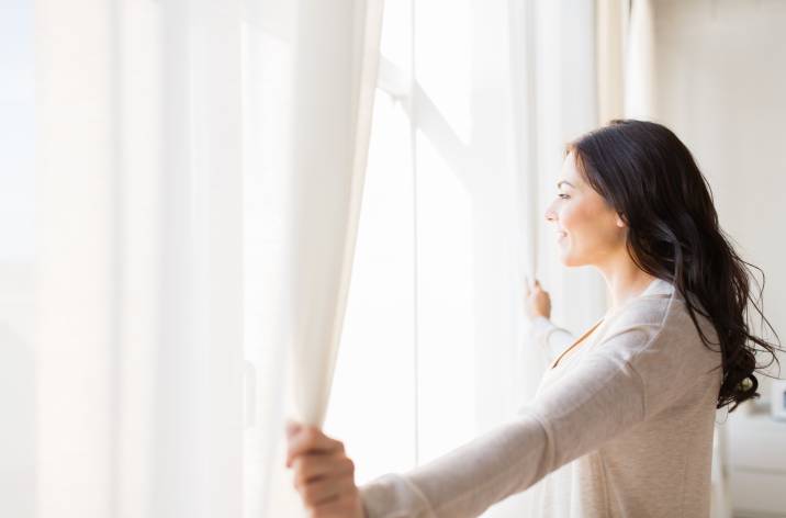 woman opening her sheer curtains