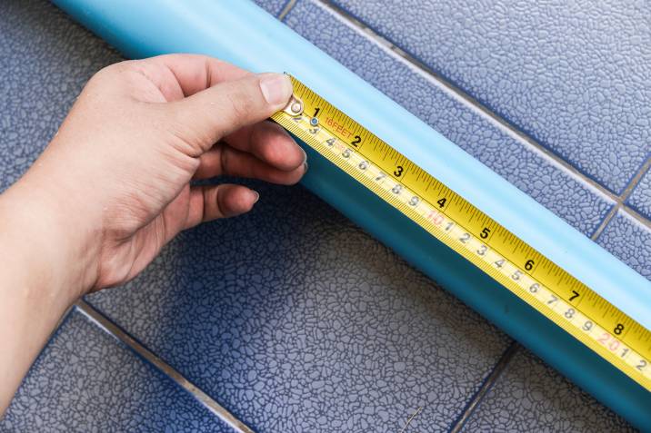 picture of a hand holding a tape measure against a PVC pipe