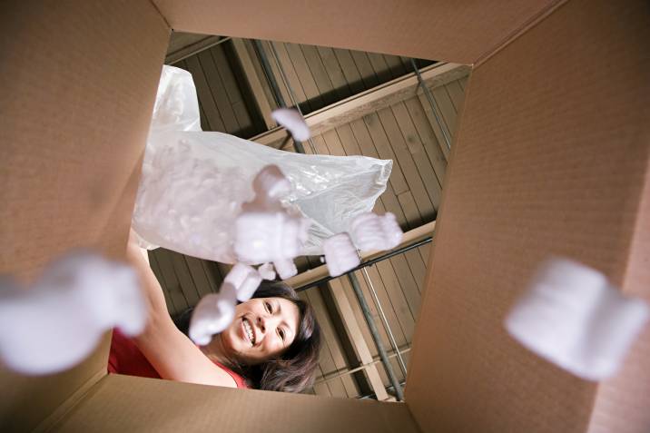 woman filling extra space in a box with packing popcorn