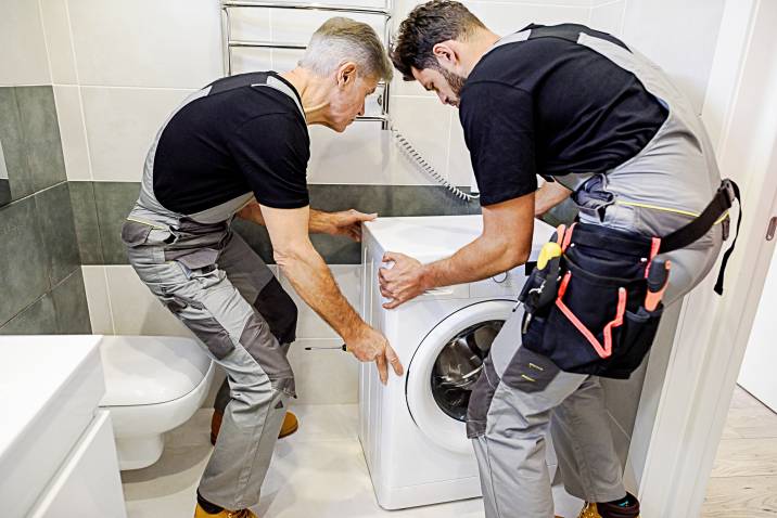 two men lifting a washing machine