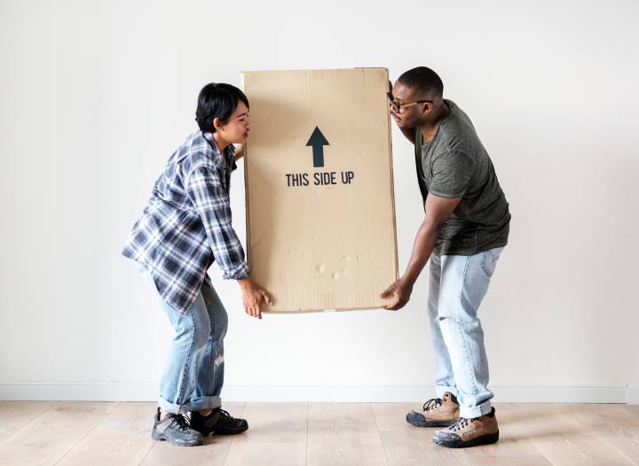 two people carrying a heavy box together