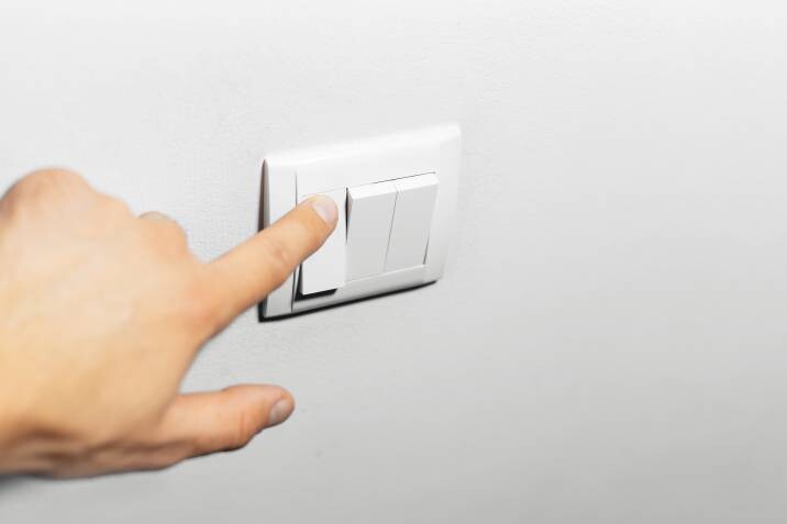 a hand turning on the light switch