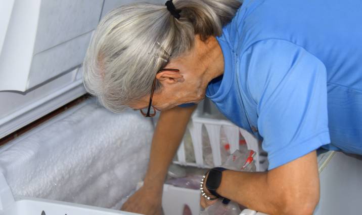 an old woman emptying a deep freezer