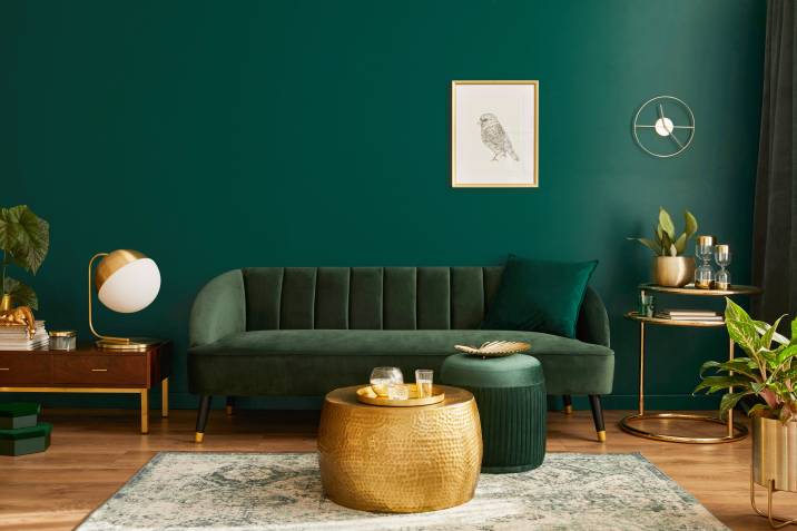 Luxury living room in apartment. Green velvet sofa, gold coffee table and decorations