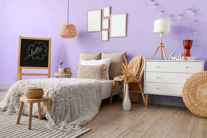Stylish bedroom with lavender-coloured wall and comfortable bed