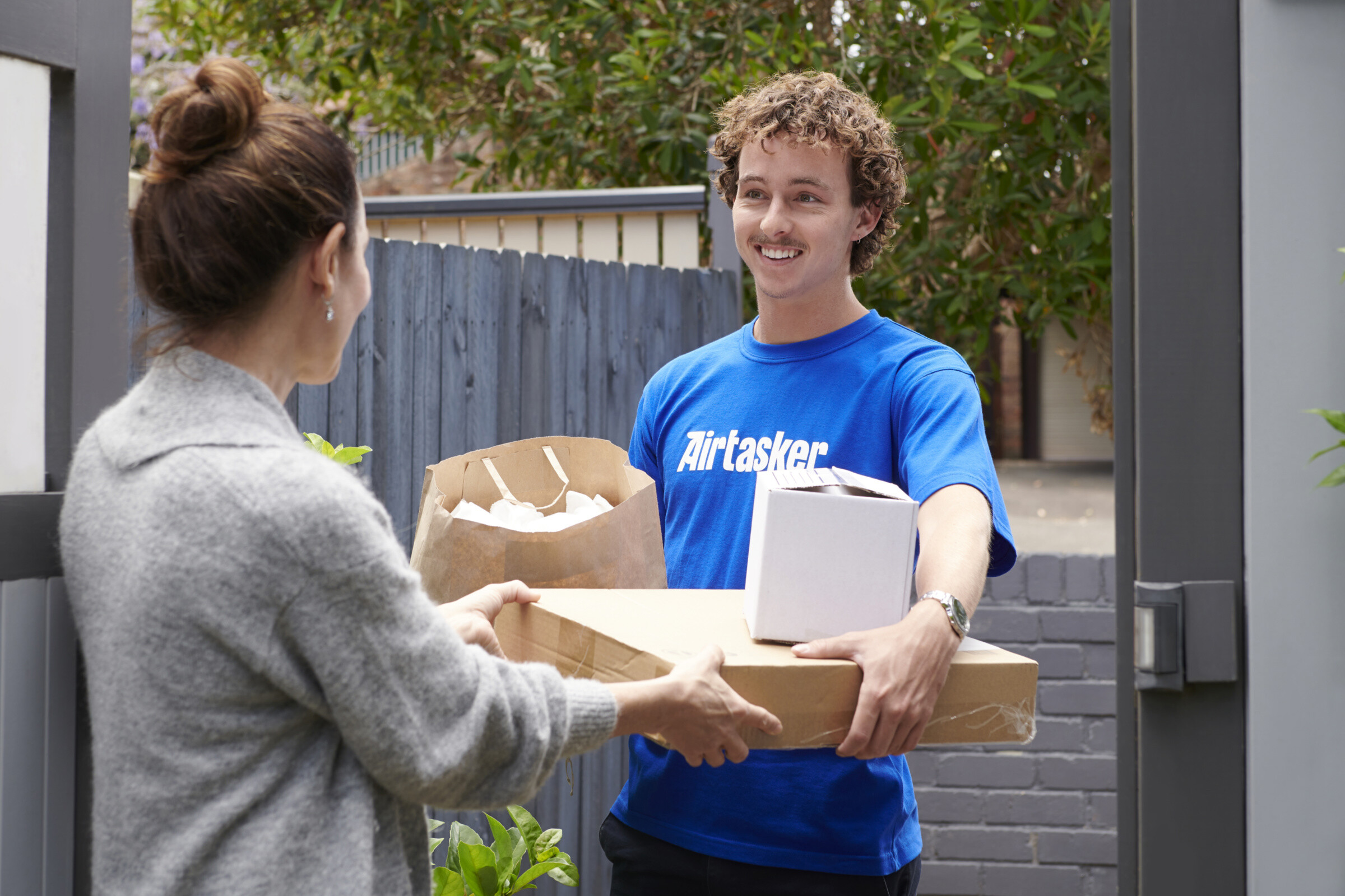 A large parcel being delivered by a courier, with the courier holding the package and walking towards a house.
