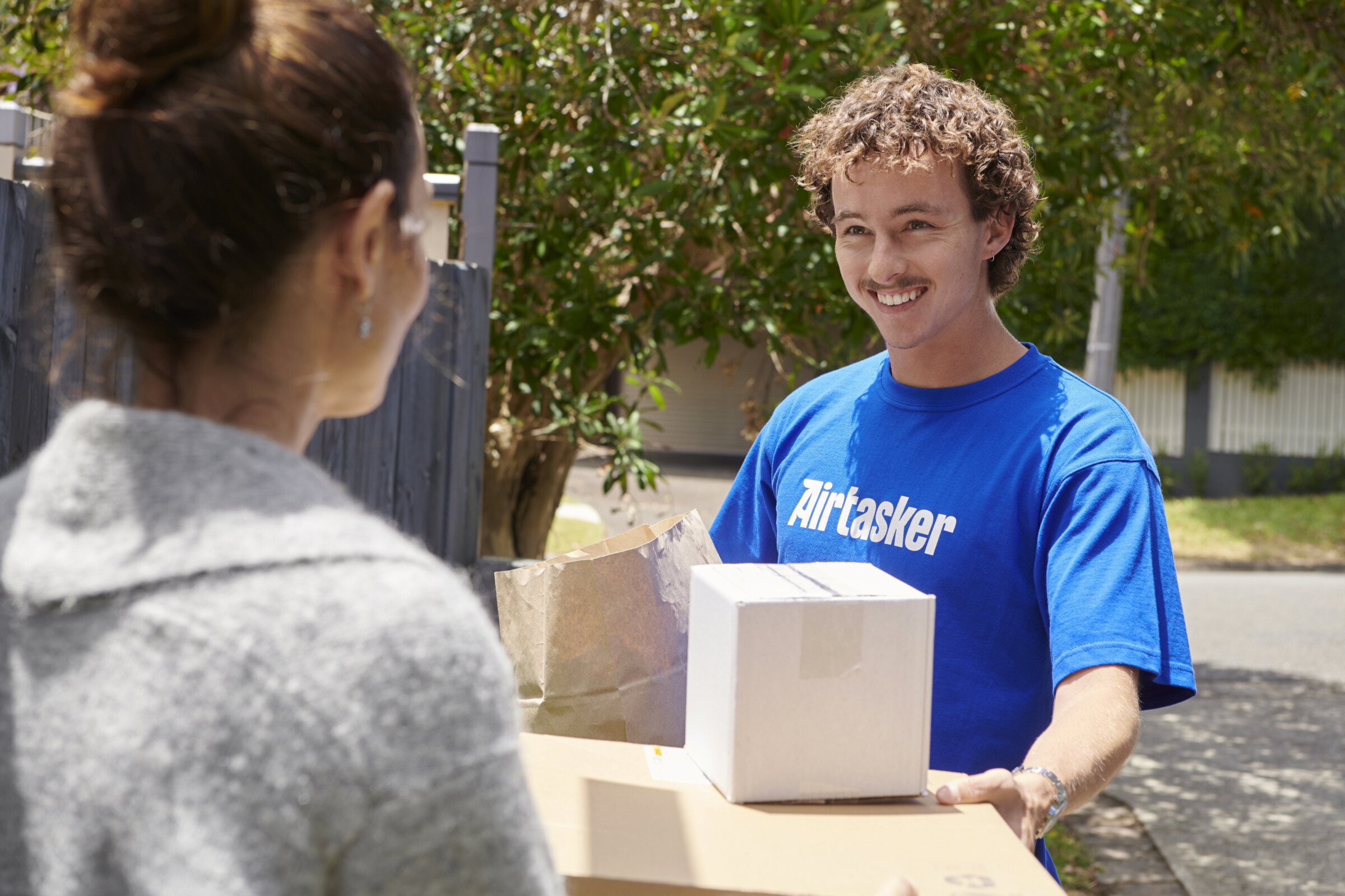 A delivery courier handing off packages to the recepient.
