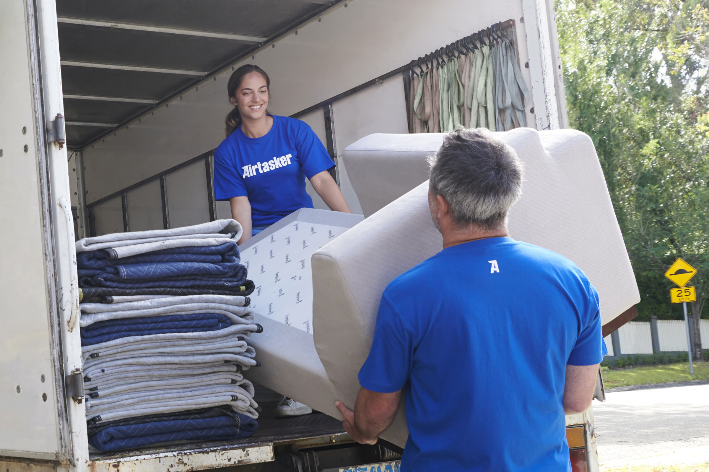 A group of movers carrying furniture and boxes into a house, symbolizing a professional and efficient removals service.