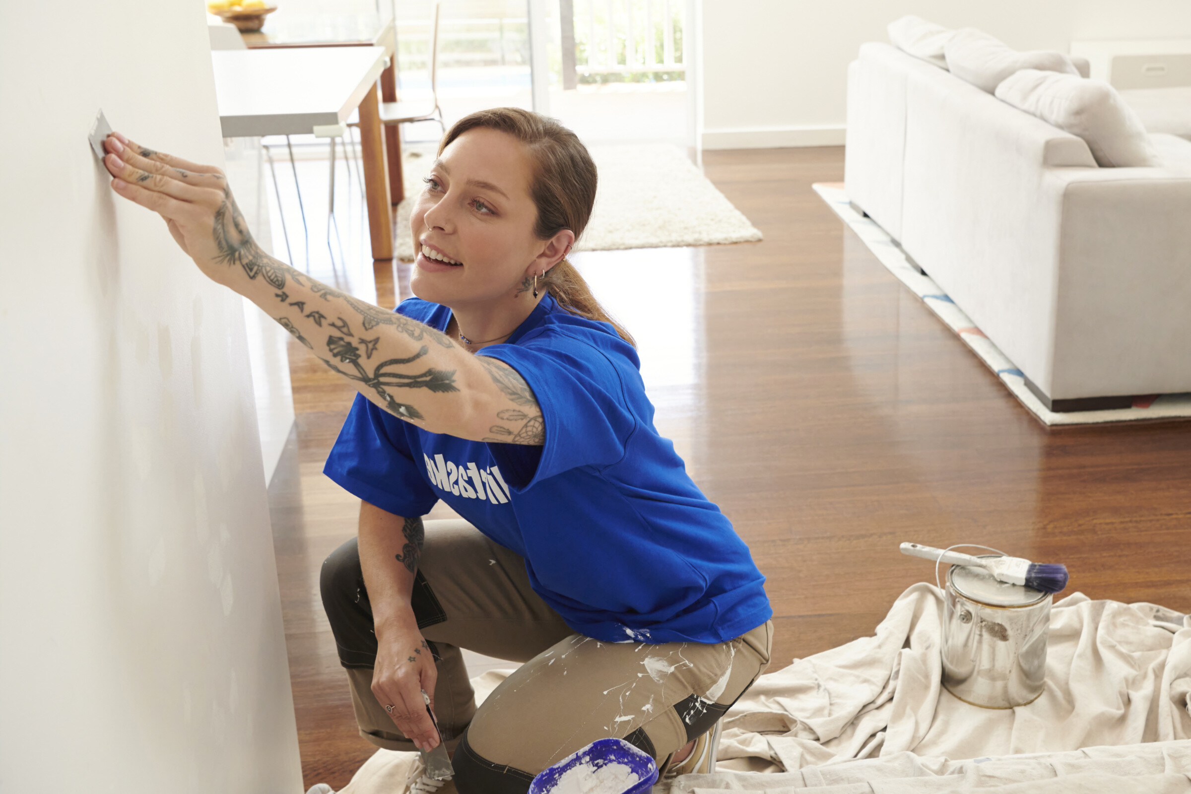 A person repairing a drywall with a putty knife and joint compound, creating a smooth surface.