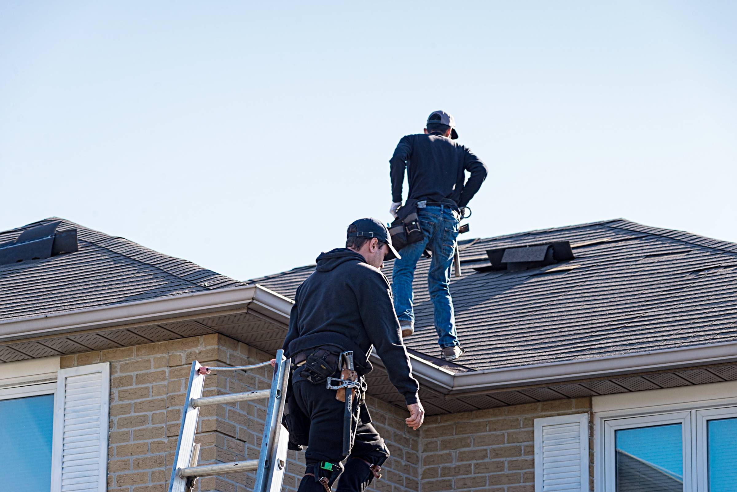 two men inspecting a damaged roof