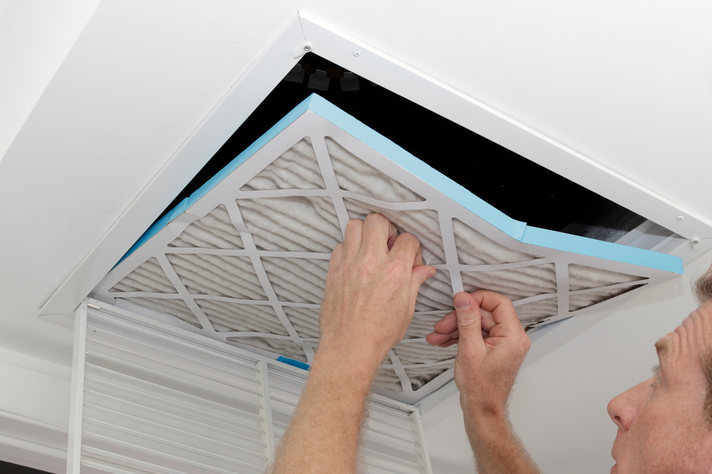 A professional taking out the filter of a ceiling air duct.