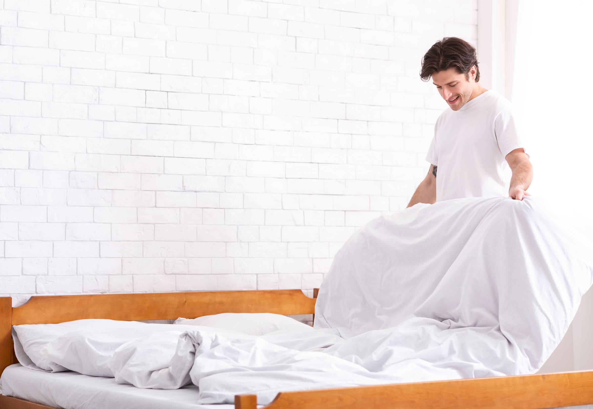 a man making his bed in the morning