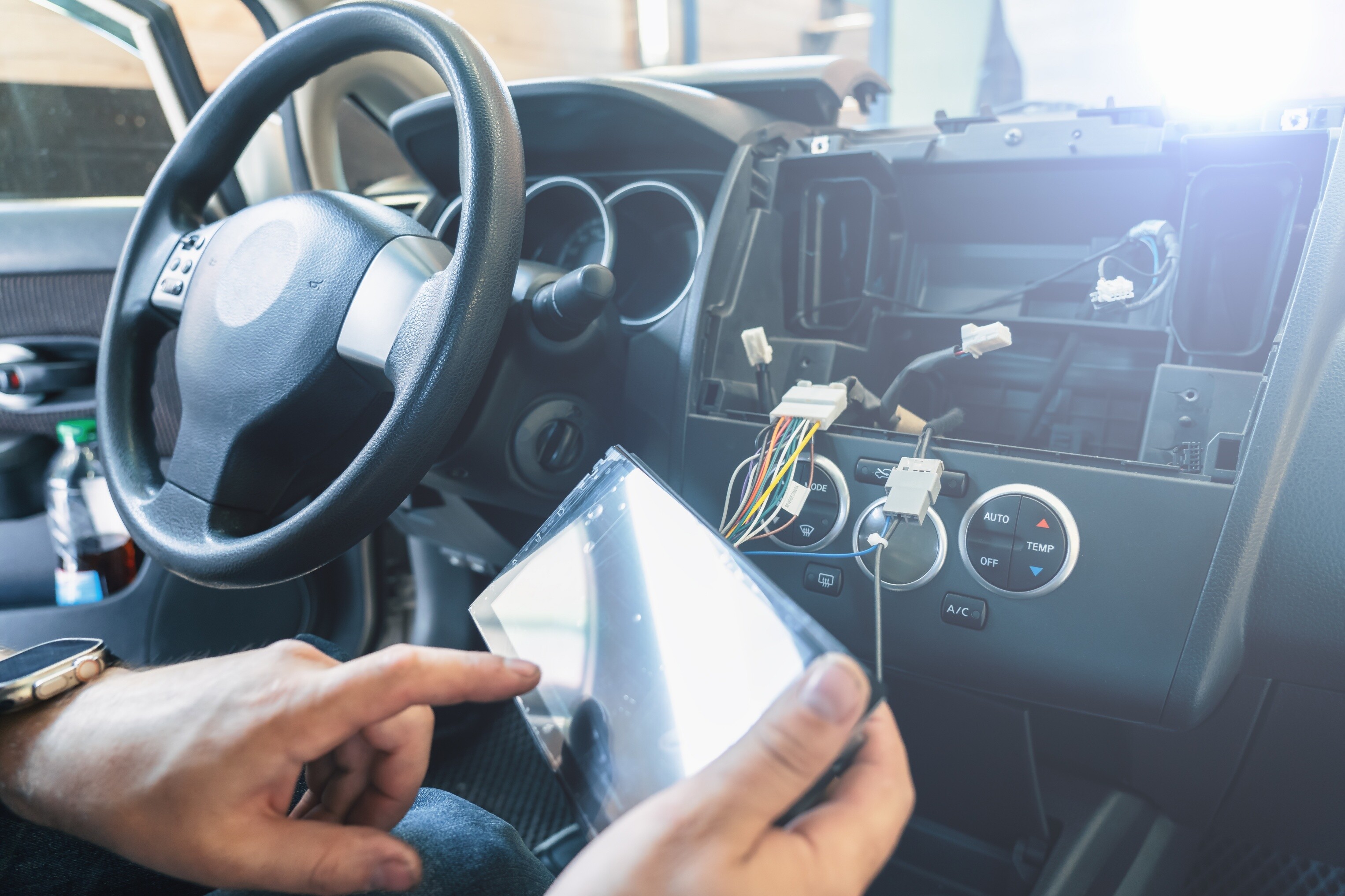 Close-up view of car stereo installation, head unit is detached from the dash.