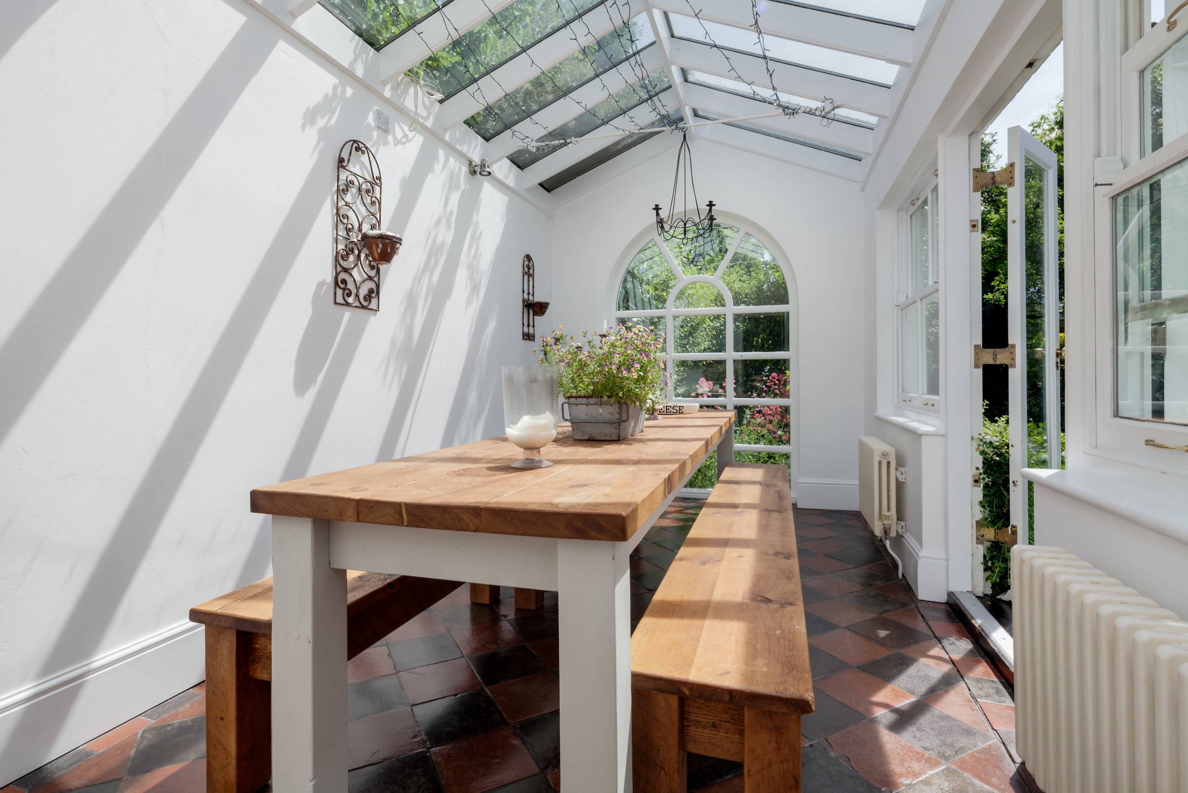 a white orangery with a table and two benches