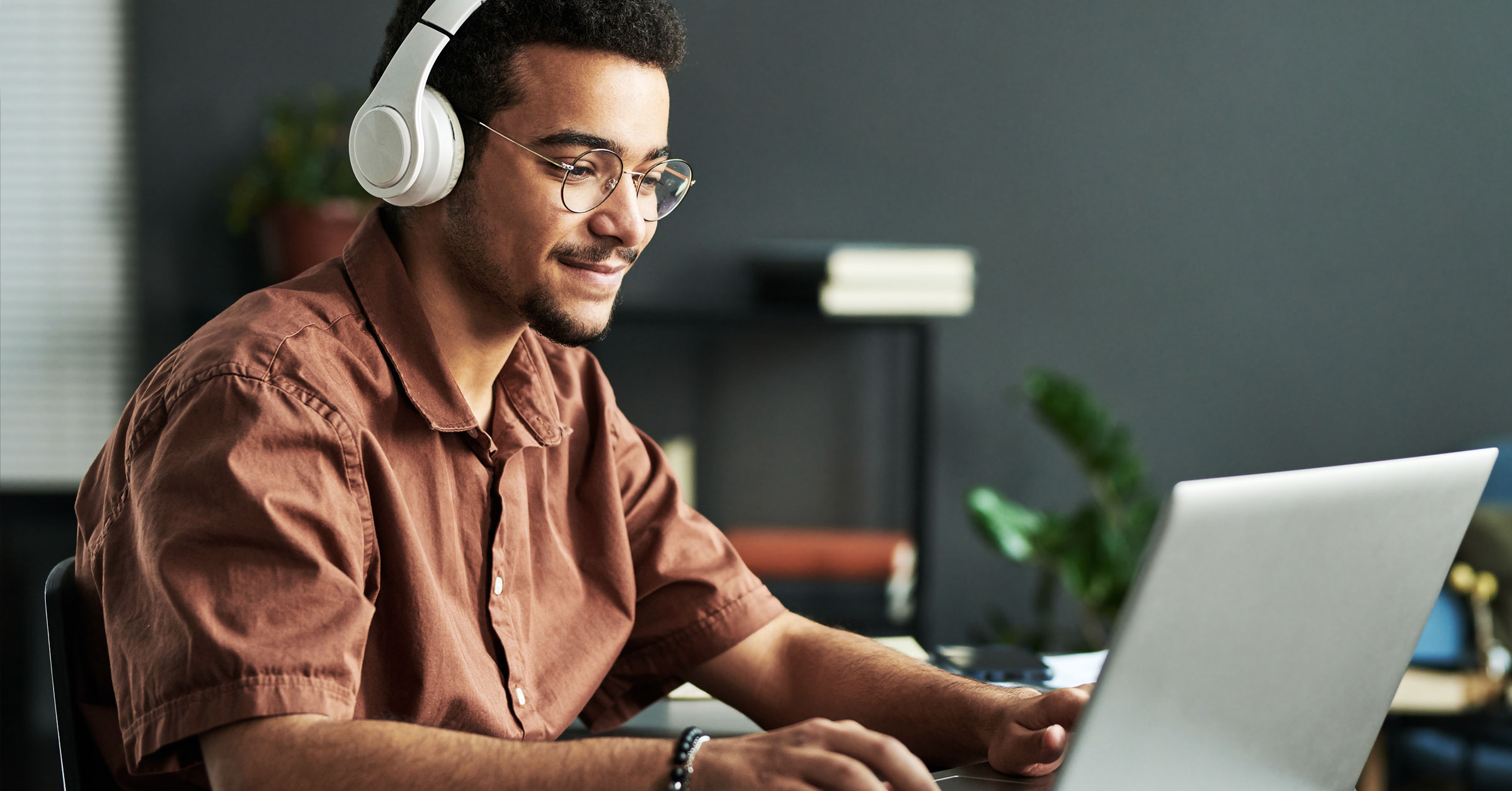 A professional writer wearing a headset working on his desk and typing on his laptop.