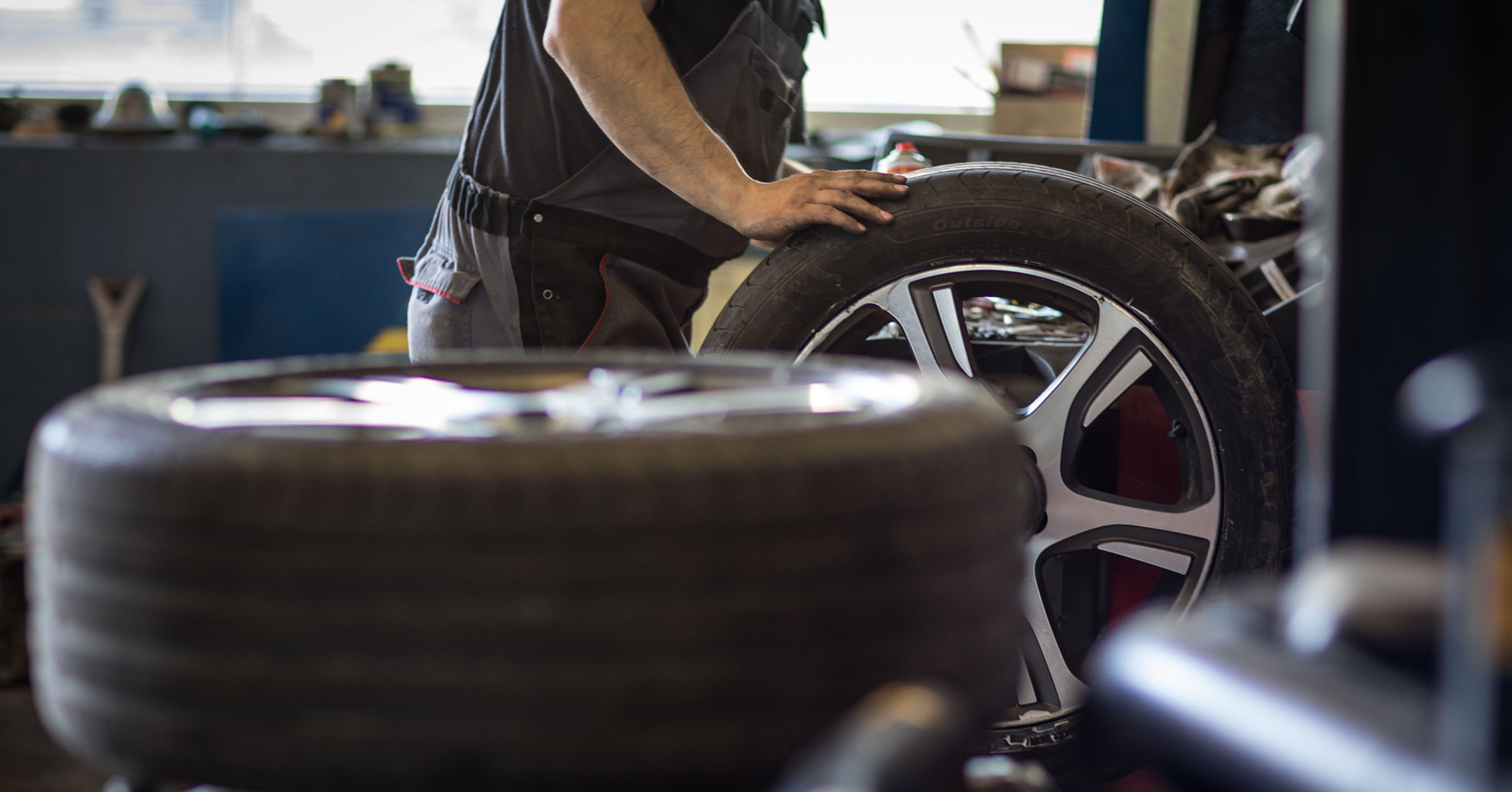 A mechanic in a shop on the way to replacing the tire on a car wheel.