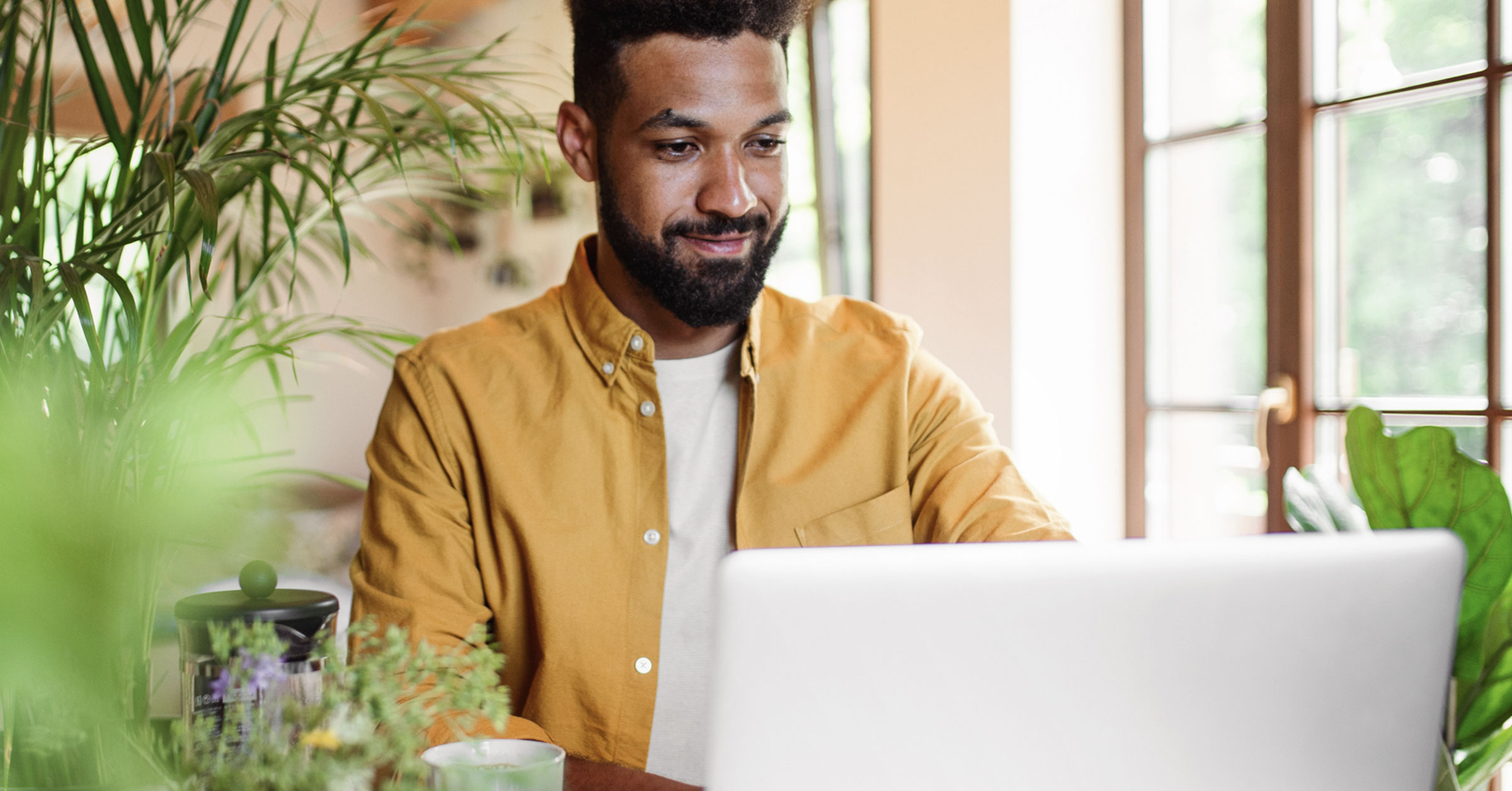 A web designer or developer working on his laptop in a comfortable room.