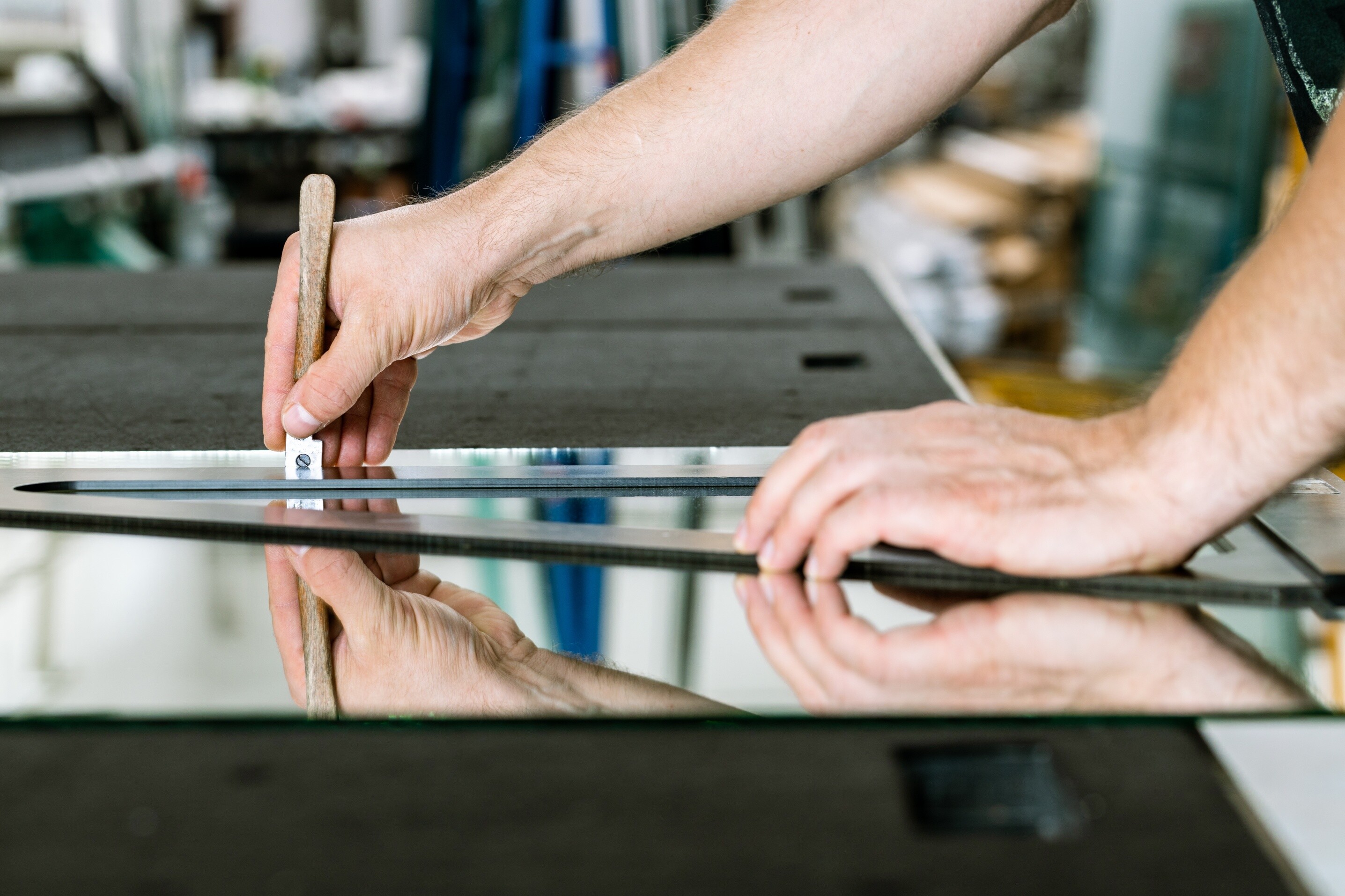 A close-up view of a glass being cut by a specialist in a workshop