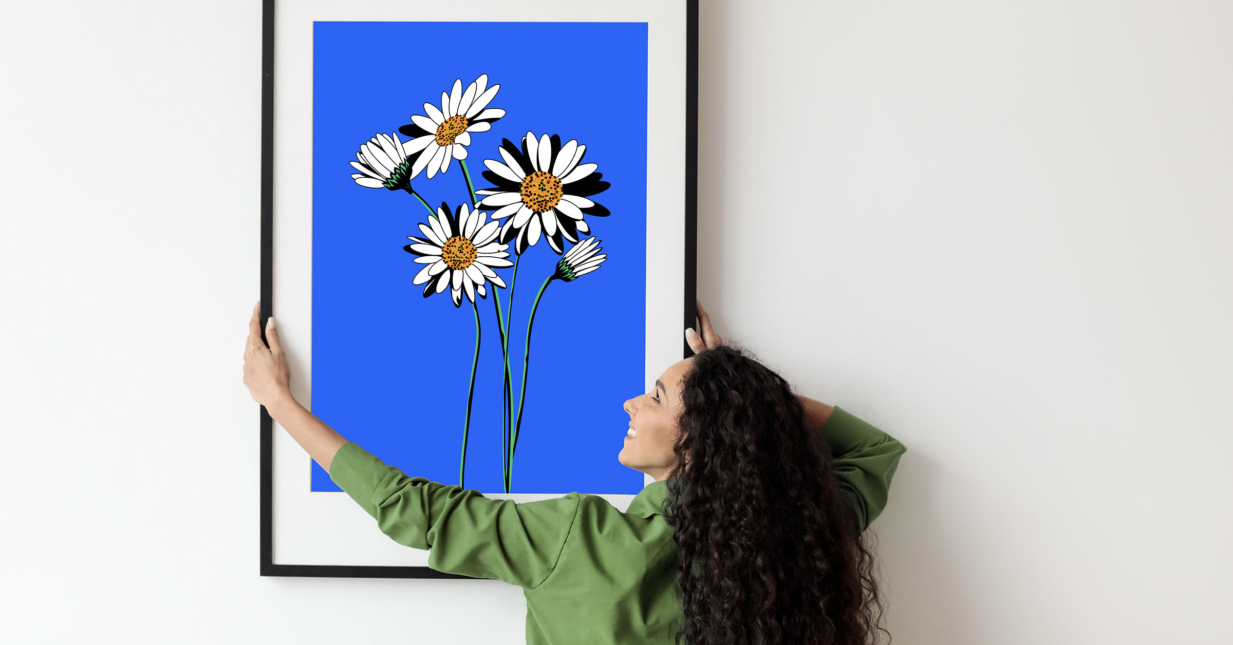 A woman in a green shirt hanging an artwork on the wall.