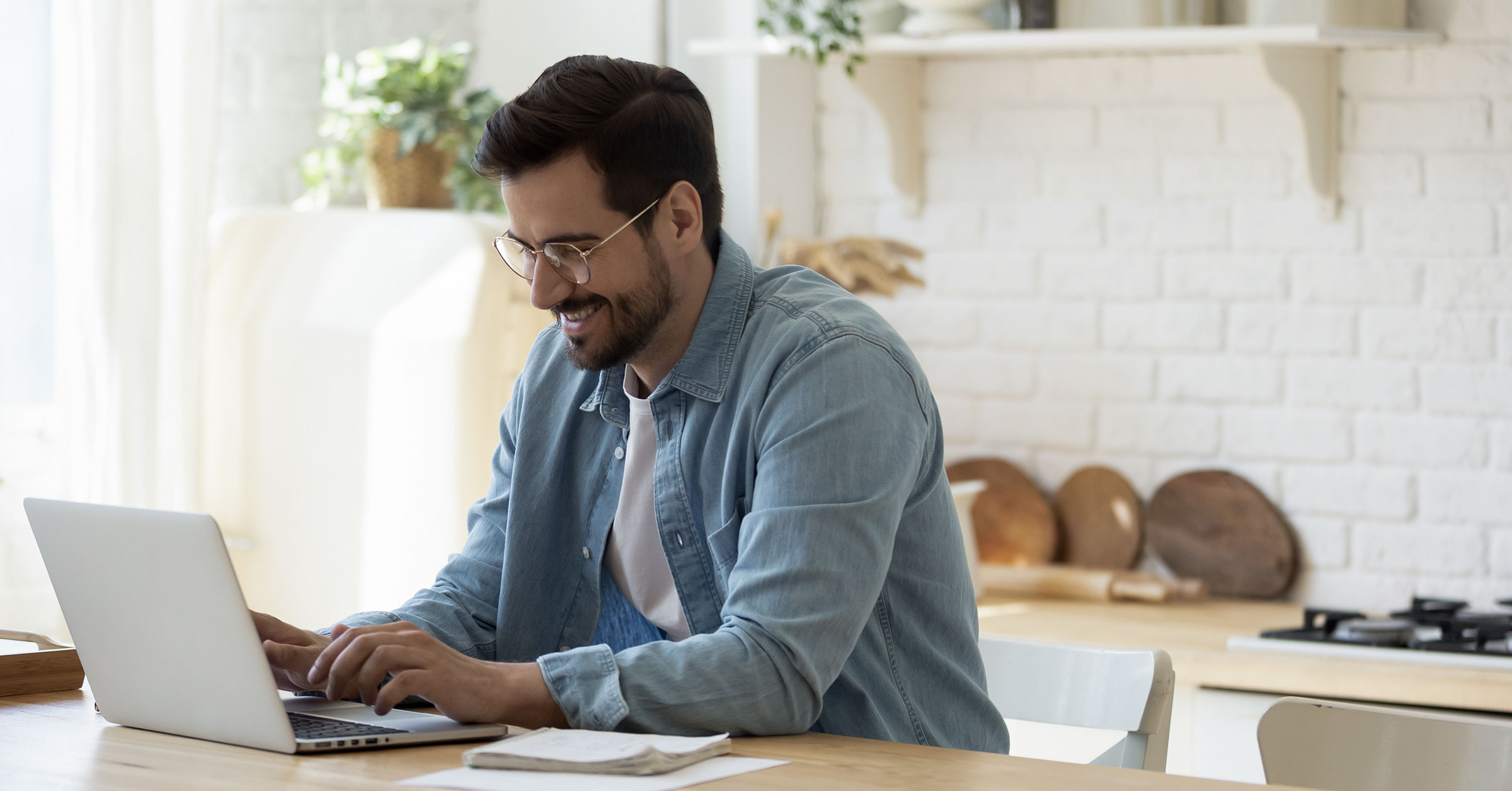 A pleasant-looking fellow working on his laptop in the kitchen. 