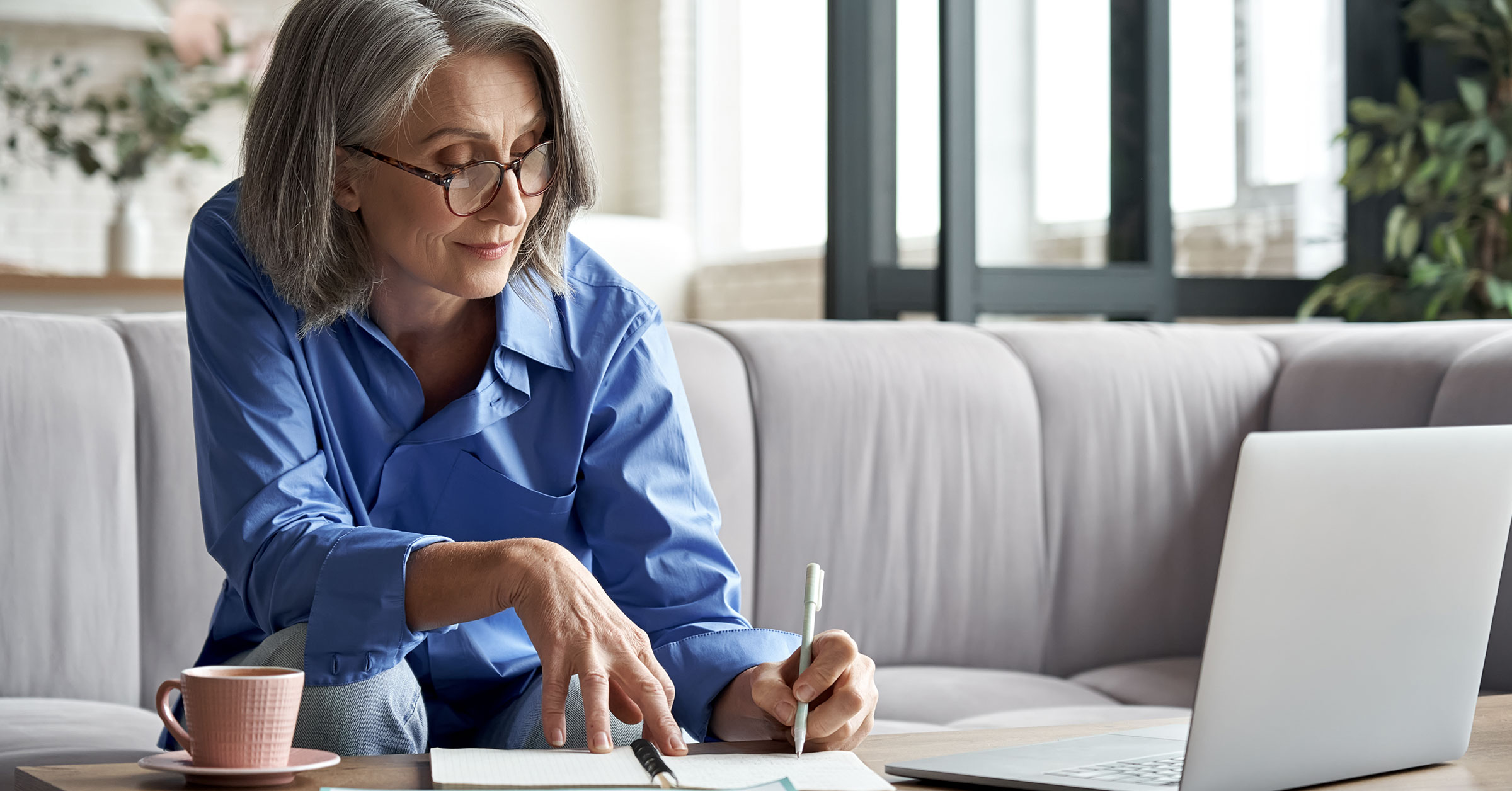 A pleasant lady taking notes on her notebook while conducting an online lesson.