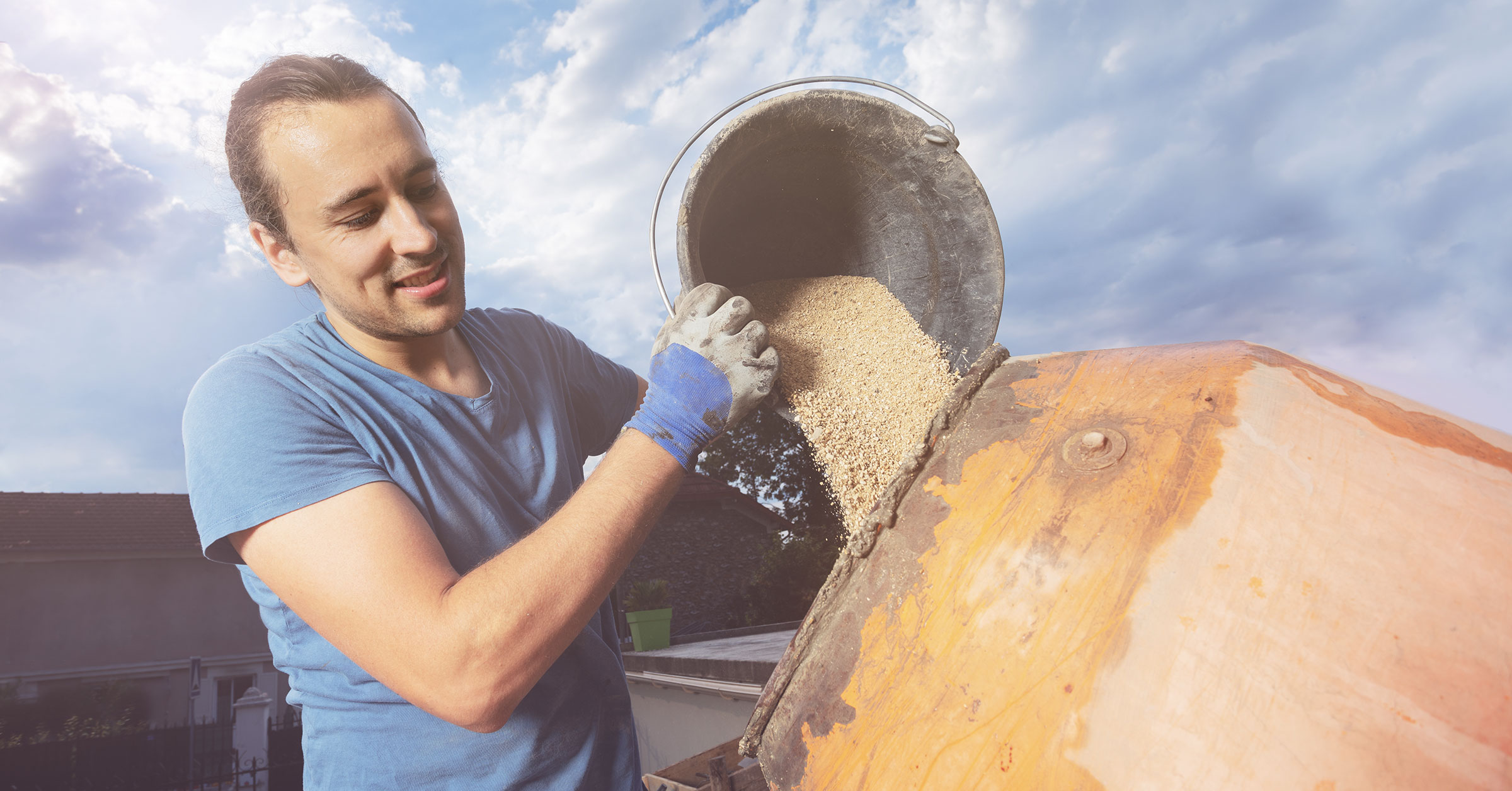 A photo of a professional builder placing concrete in a cement mixer.