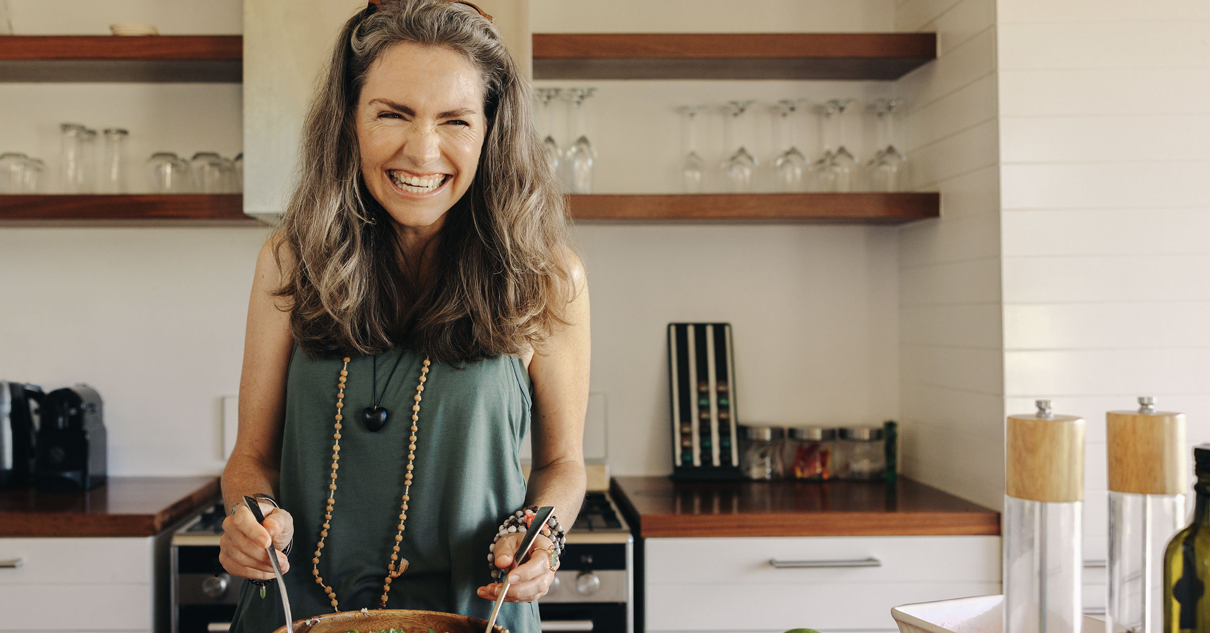 A photo of a woman smiling as she prepares catering food in a well organised kitchen