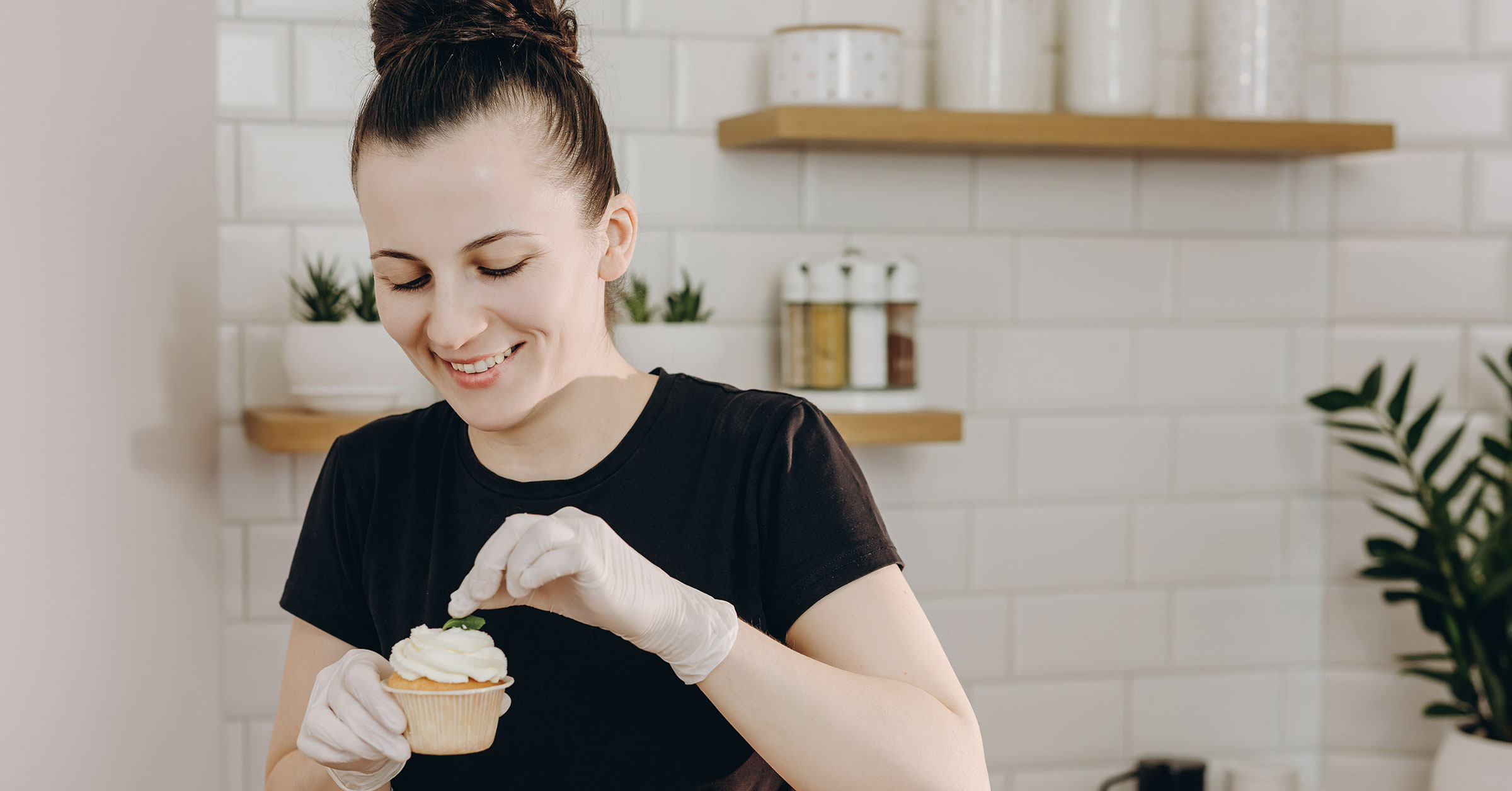 An image of a baker placing topping on a cupcake