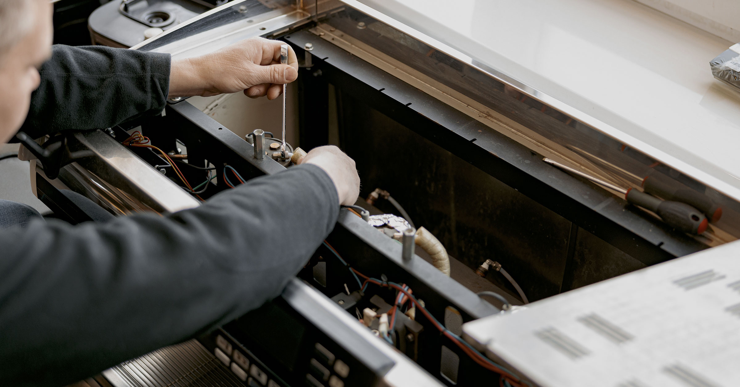 A top view, close up image of a professional working on repairing a kitchen appliance