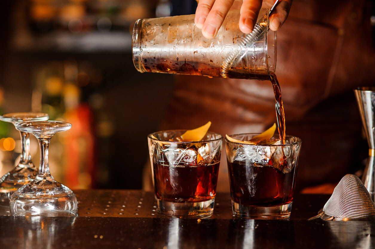 bartender pouring cocktails into glasses
