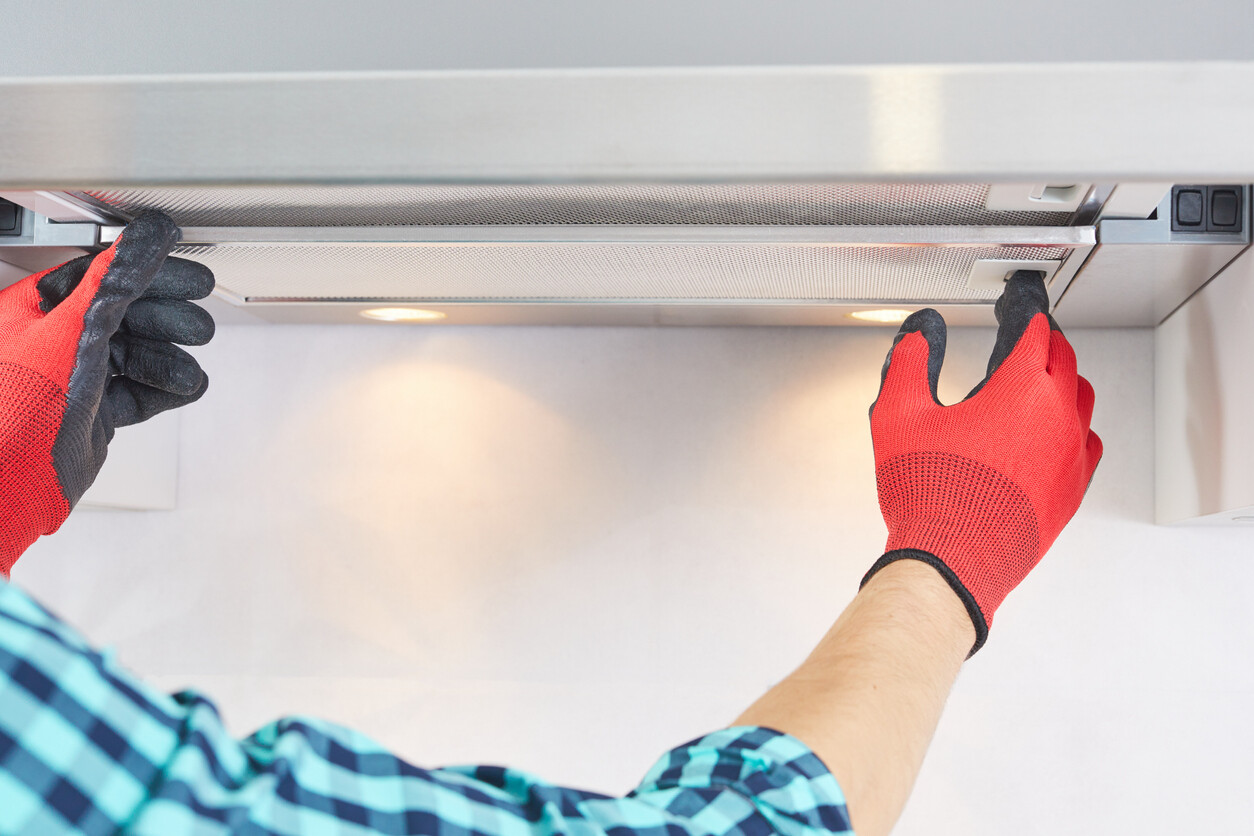 person securing the range hood hinges