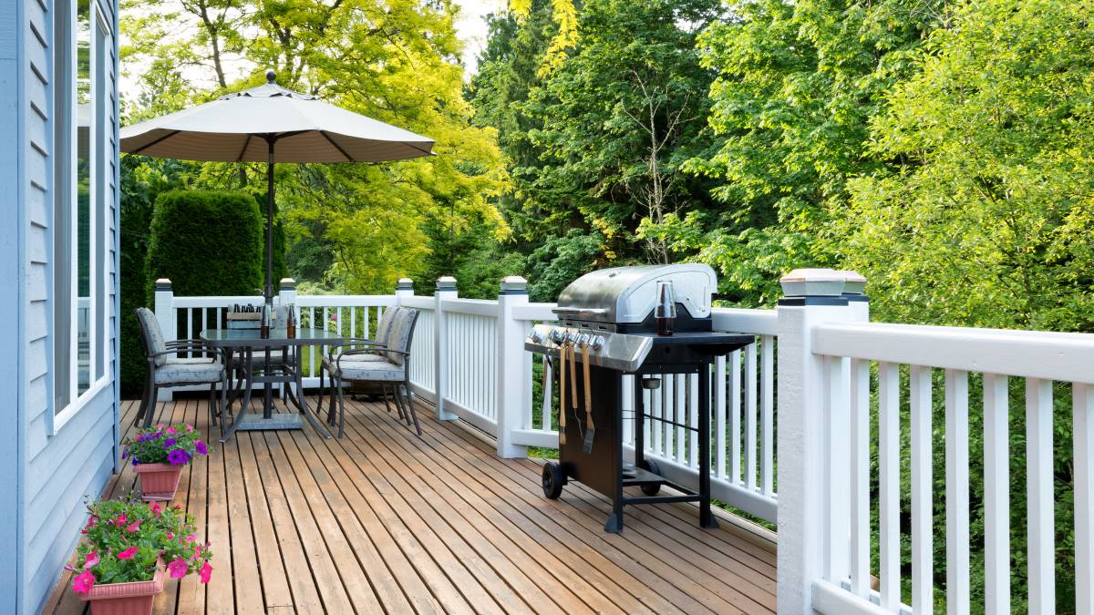 A neat wooden deck with a grill and dining area