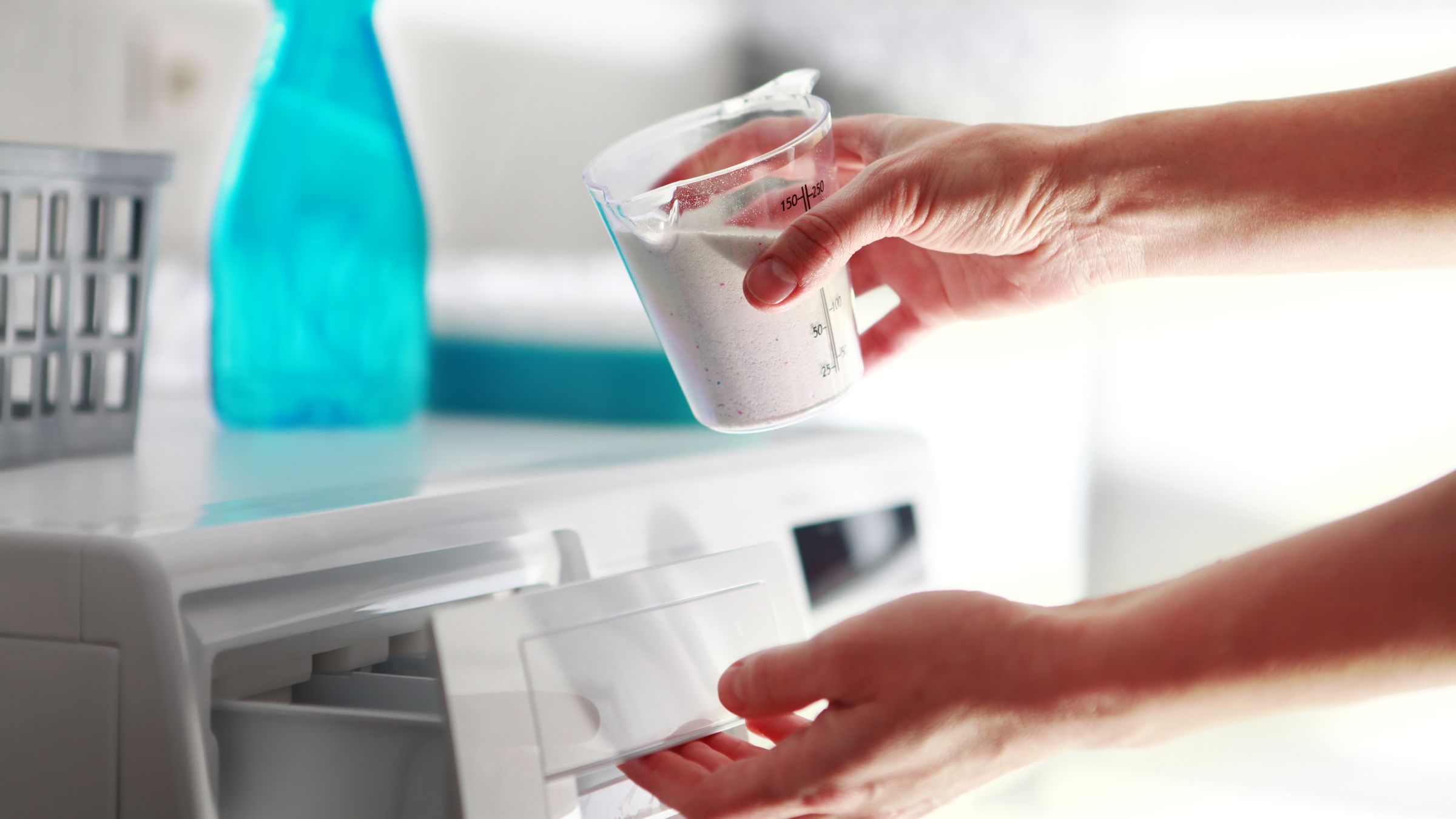 hands of woman that fills bio or non-bio detergent in the washing machine