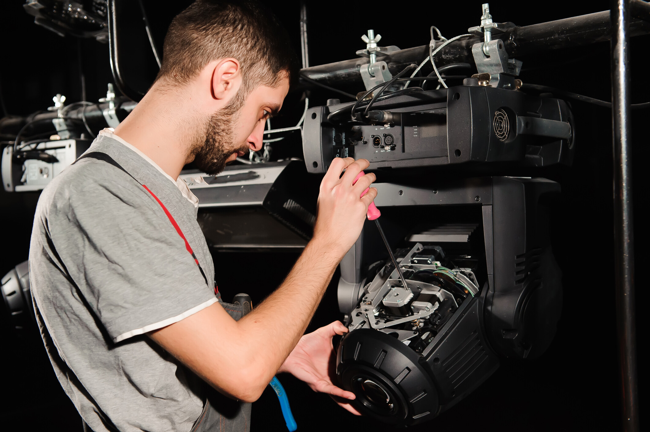 An audio visual technician repairing lighting equipment backstage.