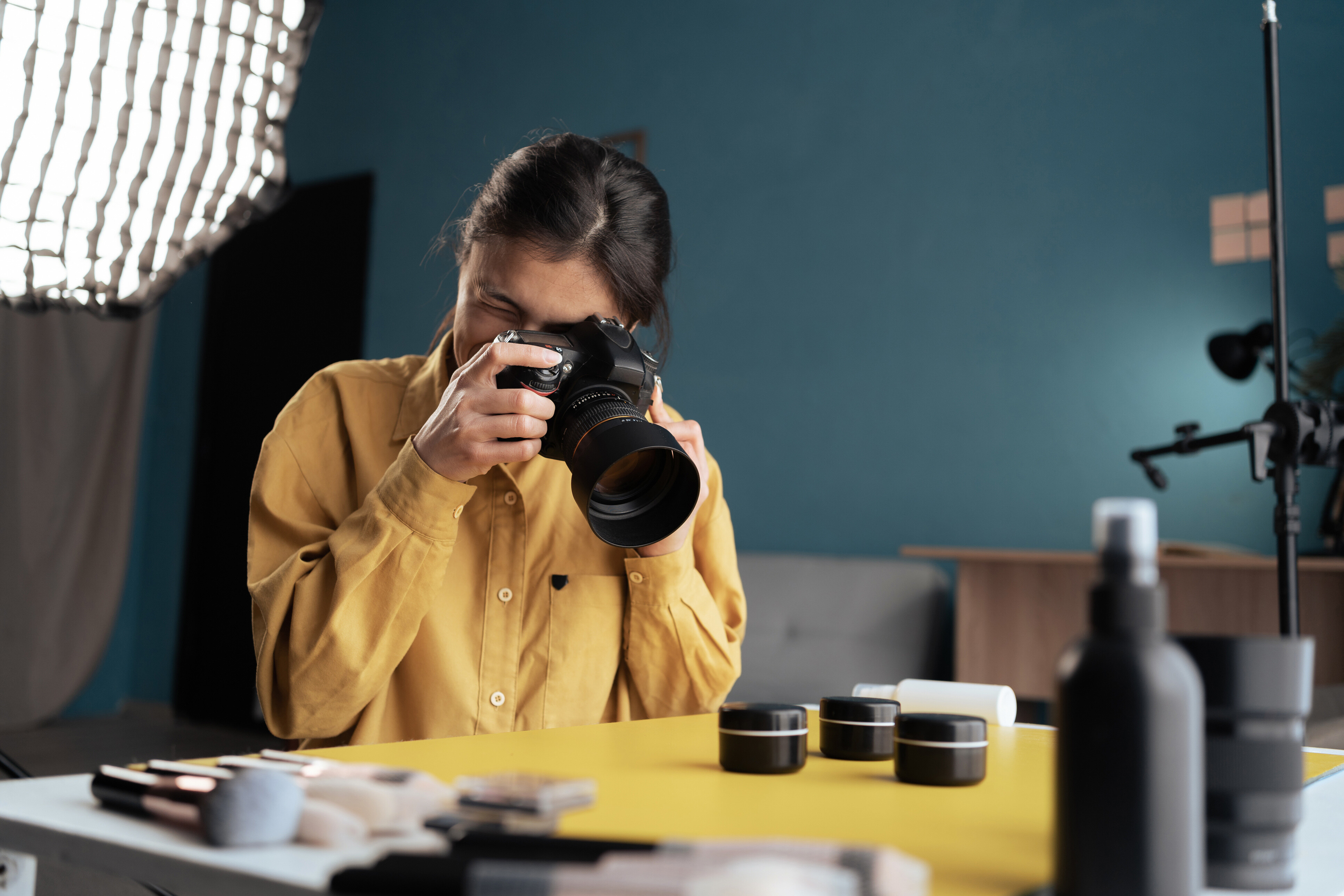 A photographer wearing a yellow short taking product pictures in a studio.