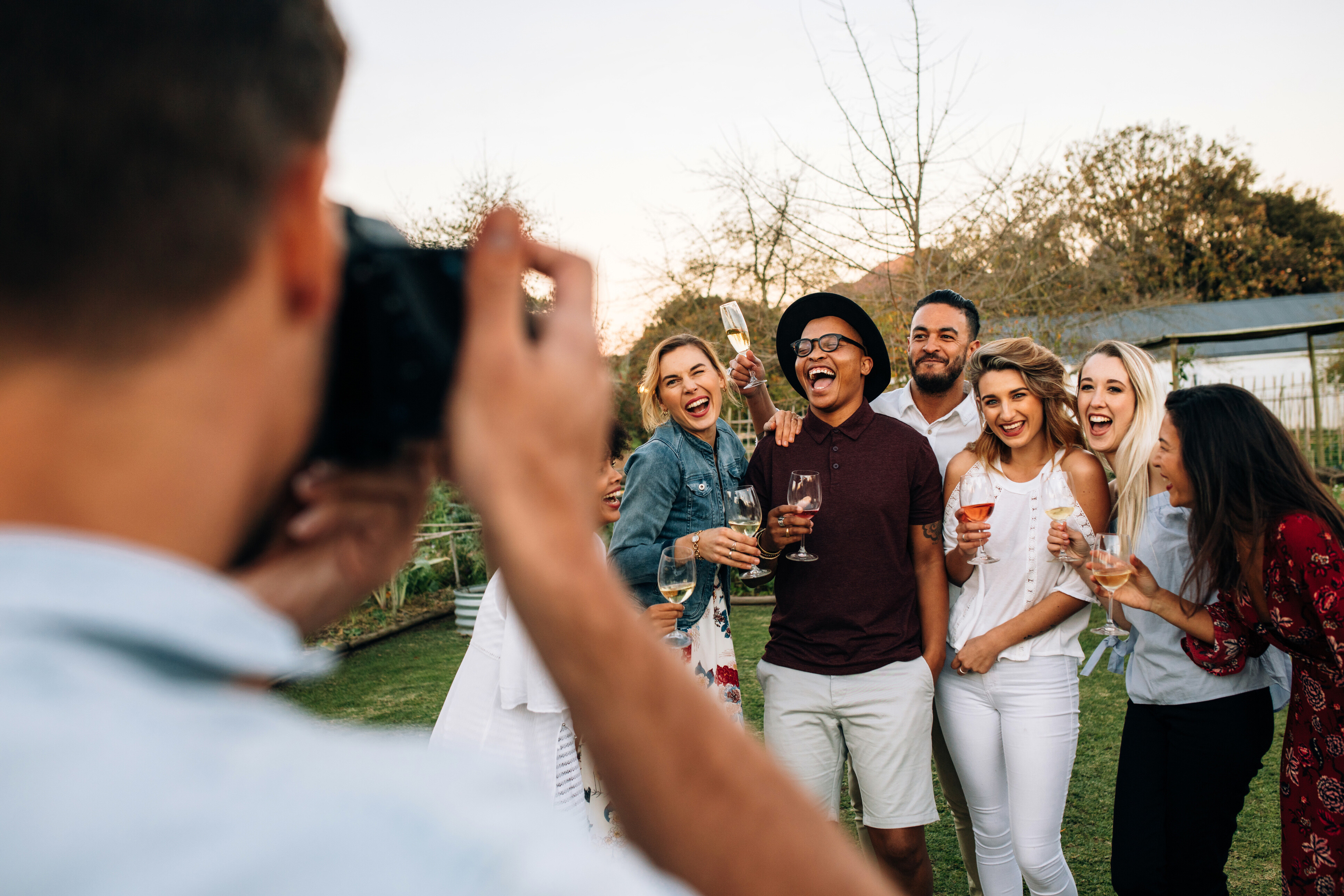 An event photographer taking a picture of a diverse group of people during an event at a garden.