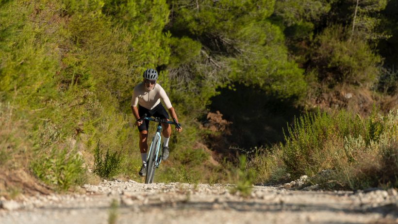 A male cyclist in a mediterranean forest to show what is a gravel bike