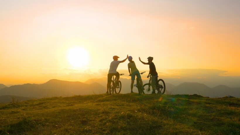 Mountain biking friends high five as they compare the difference between a gravel bike vs road bike in terms of terrain versatility