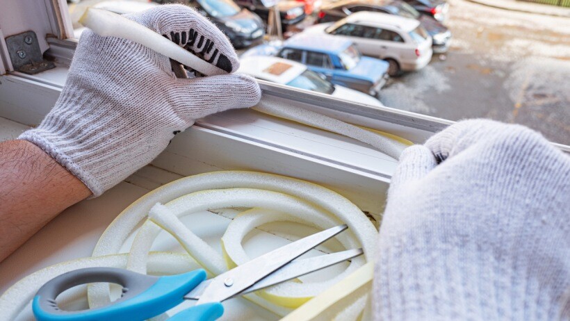 foam weather stripping vs vinyl: a man with gloves installing foam weather stripping to improve house ventilation