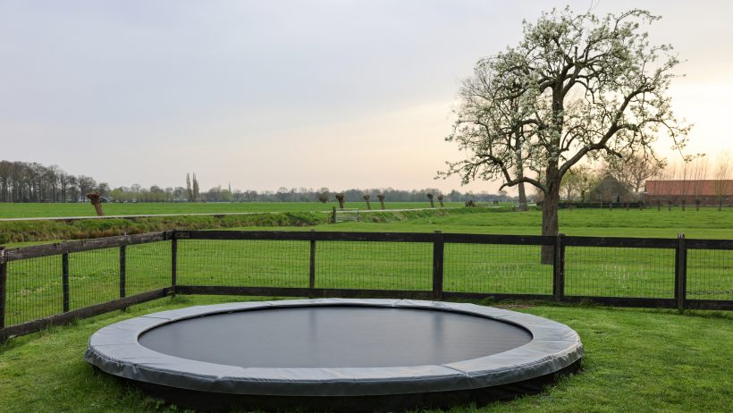 rectangle vs round trampoline: spacious backyard with a round trampoline and wooden fence