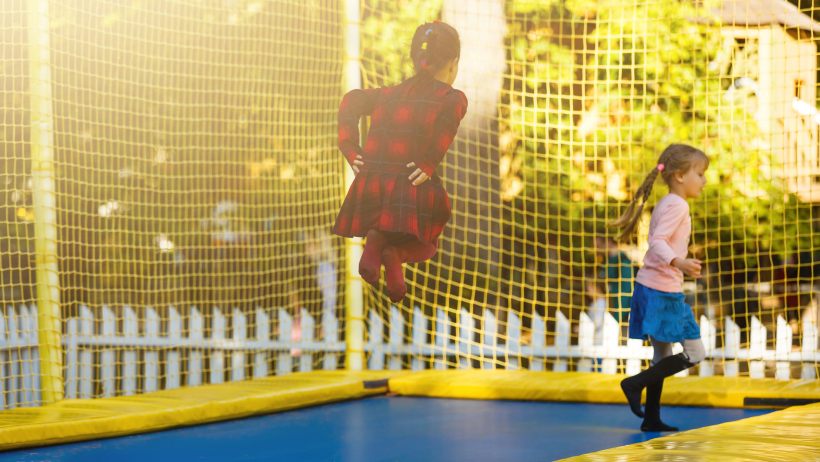 rectangle vs round trampoline: happy school girls safely jumping on a rectangle trampoline