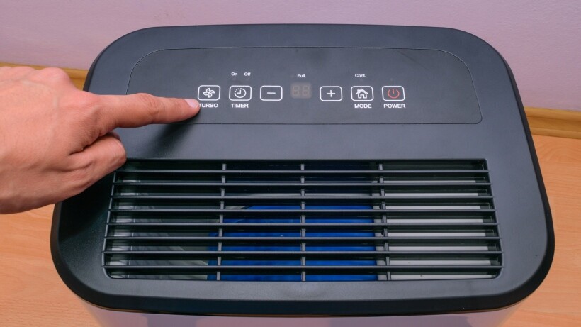 Air purifier vs dehumidifier: A person's hand setting up house hold dehumidifier