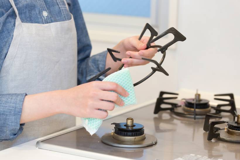 a woman cleaning the gas stove - induction vs gas cooktop