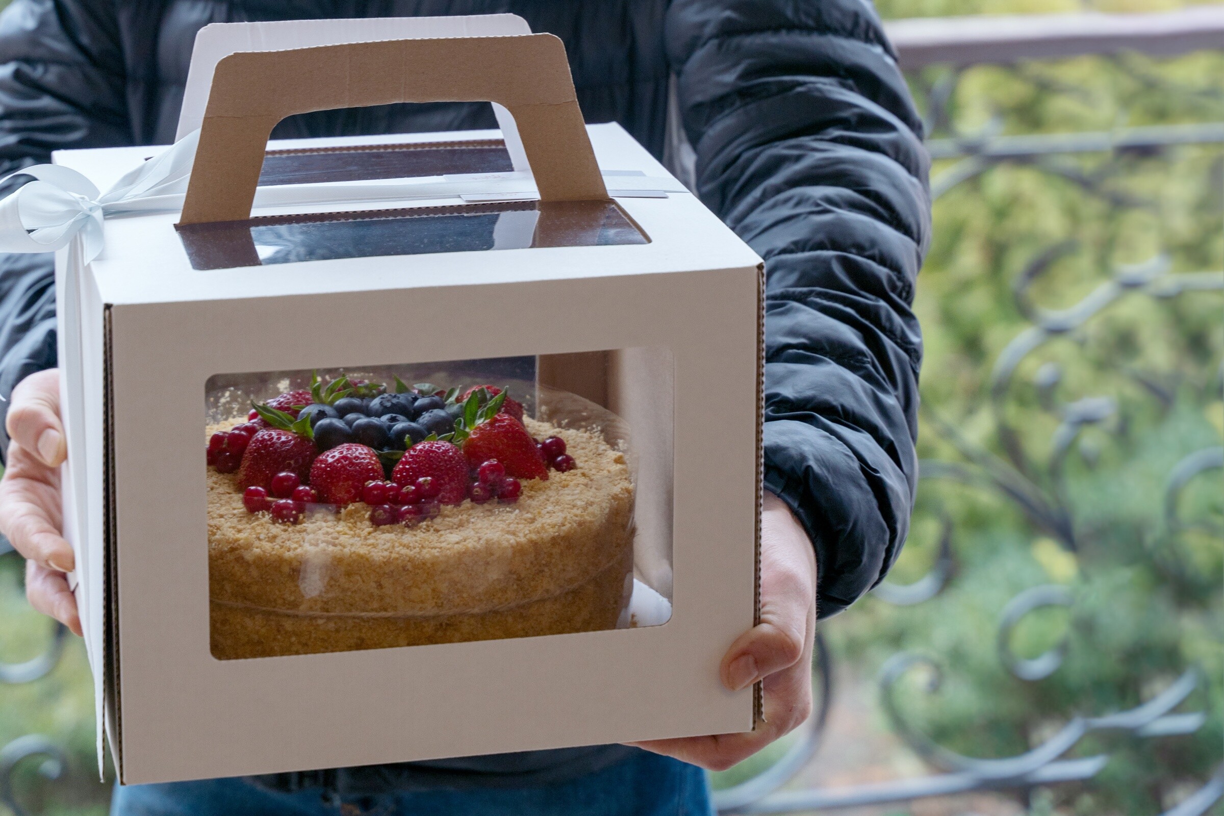 A man delivering a cake with berries on top.